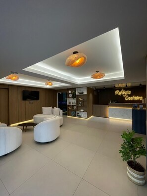 A modern lobby with a reception desk, seating area, and decorative lighting. - Pousada Refúgio Costeiro (Bombinhas)