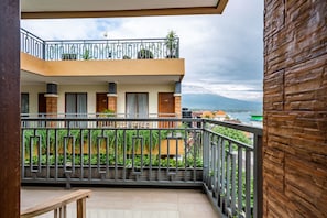 Enjoy breathtaking views of the water and distant mountains from this building's spacious balcony, featuring a metal railing and lush potted plants.