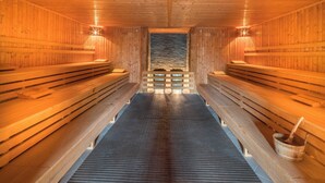 A sauna with wooden benches and a stone wall at the back. - Castello Apartments (Adendorf)