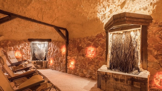 A stone-walled room with a fireplace, a lounge chair, and a small table. - Castello Apartments (Adendorf)