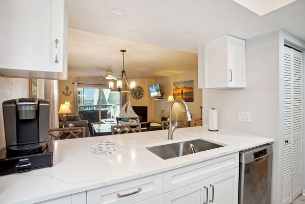 A modern kitchen with a built-in dishwasher, a coffee maker, and a dining area with a table and chairs.
