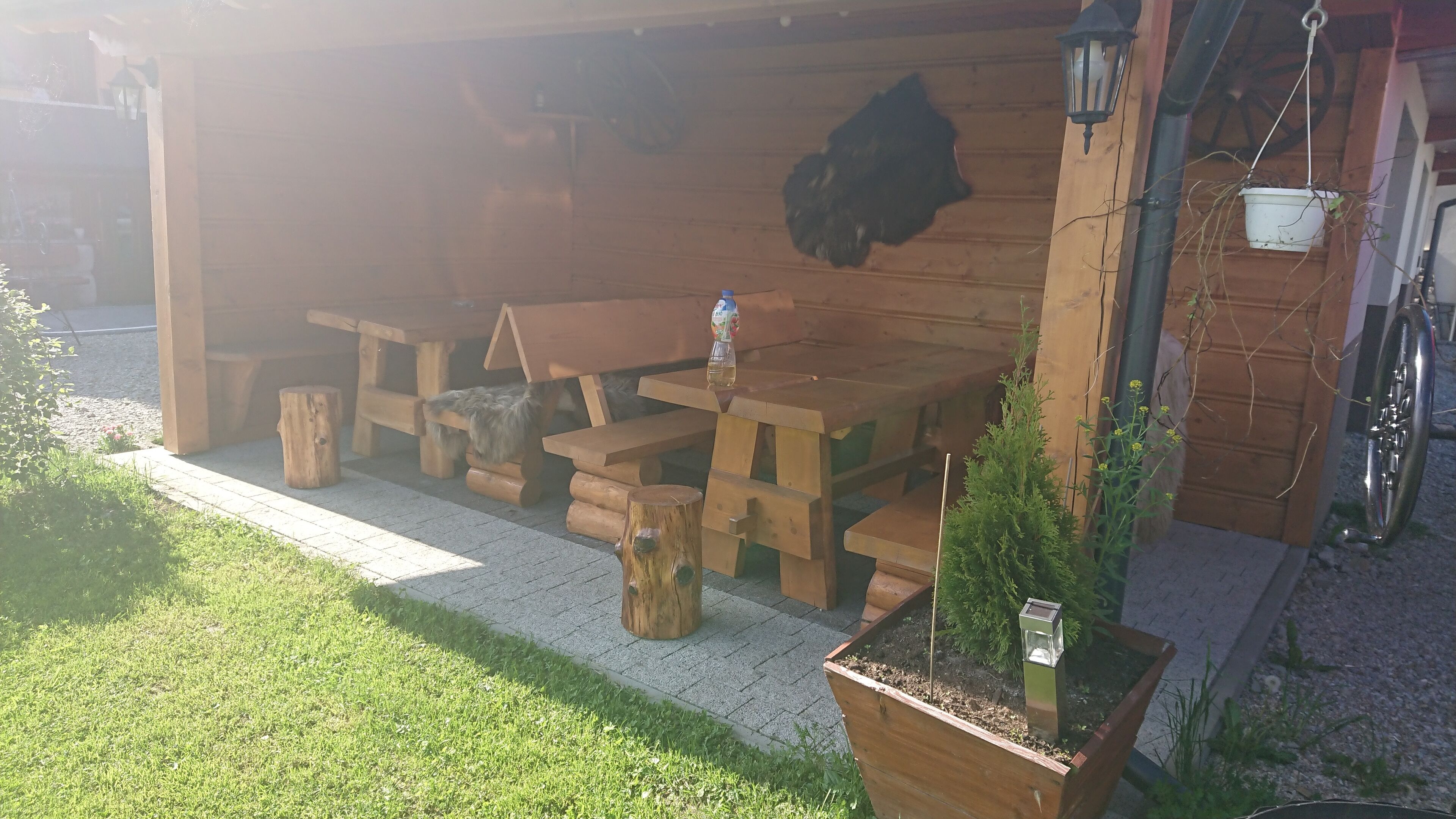 Eine Holzterrasse im Freien mit Picknicktischen und einem Blumentopf.
