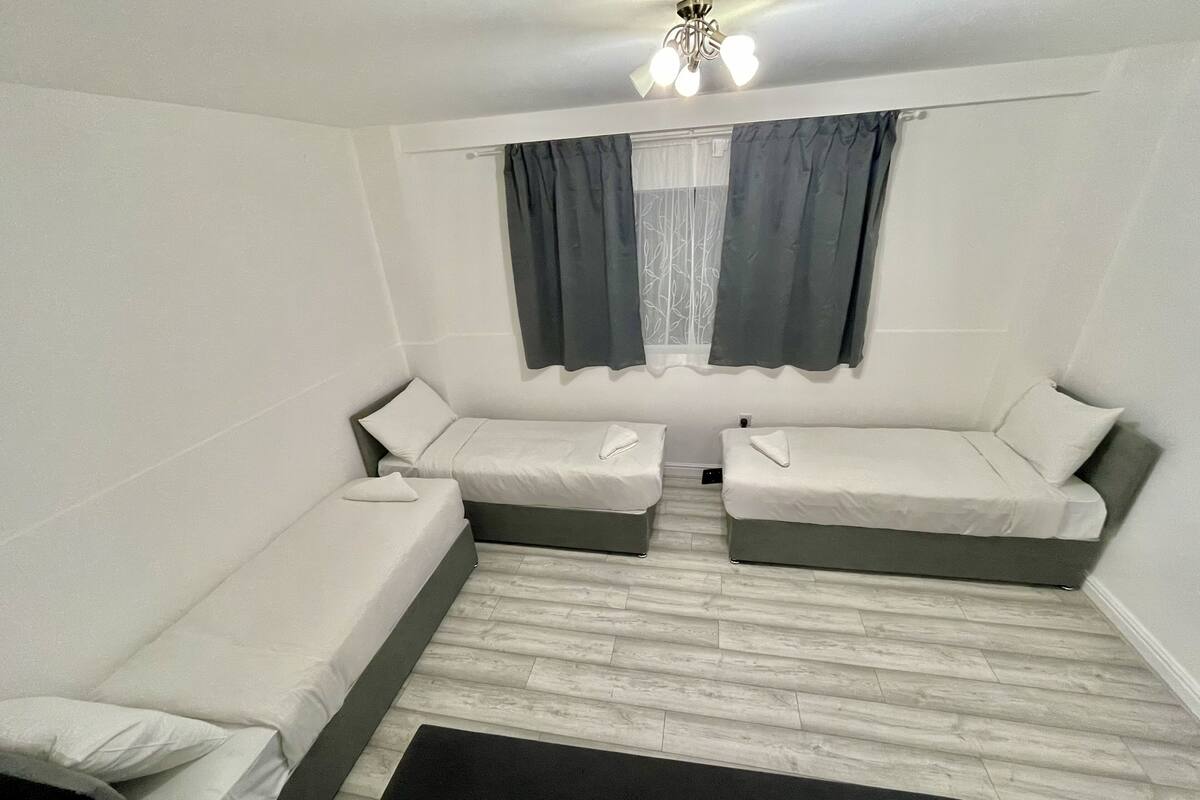 A compact room with two single beds, a small black rug, and a ceiling fan.