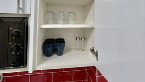 Et køkken med et hvidt skab fyldt med glas og blå krus.