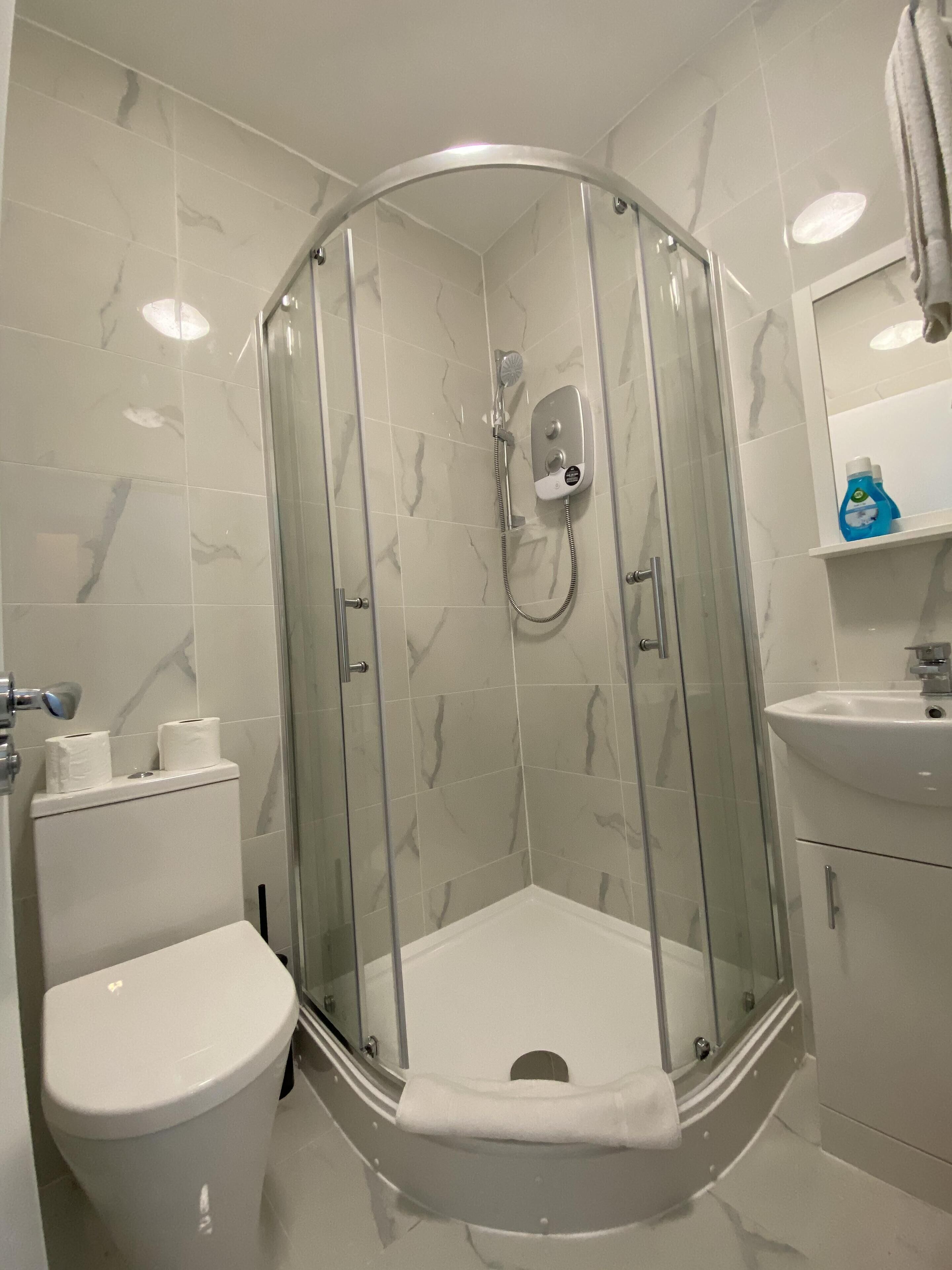 Un baño moderno con ducha envuelta en vidrio, inodoro y lavamanos.