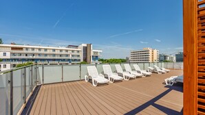 A rooftop deck with sun loungers and a view of modern buildings. - Apartamenty Sun & Snow Blizej Morza (Kolobrzeg)