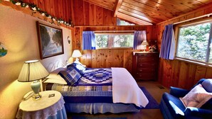 A wooden cabin bedroom with a bed, bedside lamps, a dresser, and a window with curtains. - Serenity Cabin 2 Bedroom Secluded Close to Trails! (Idyllwild)