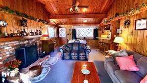 A cozy cabin interior with a fireplace, a dining area, and a living room furnished with a sofa and a coffee table. - Serenity Cabin 2 Bedroom Secluded Close to Trails! (Idyllwild)