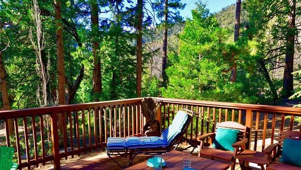 A wooden deck with a table set for four, surrounded by chairs, overlooking a forested area. - Serenity Cabin 2 Bedroom Secluded Close to Trails! (Idyllwild)