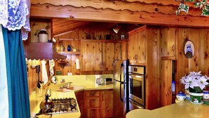A wooden cabin-style kitchen with a gas stove, refrigerator, and wooden cabinets. - Serenity Cabin 2 Bedroom Secluded Close to Trails! (Idyllwild)