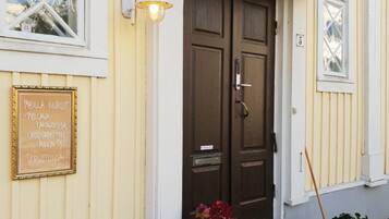 A building with a dark brown door, a light fixture above the door, and a sign on the wall.