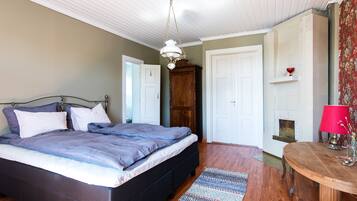 A bedroom with a bed, wooden wardrobe, white doors, and a fireplace.