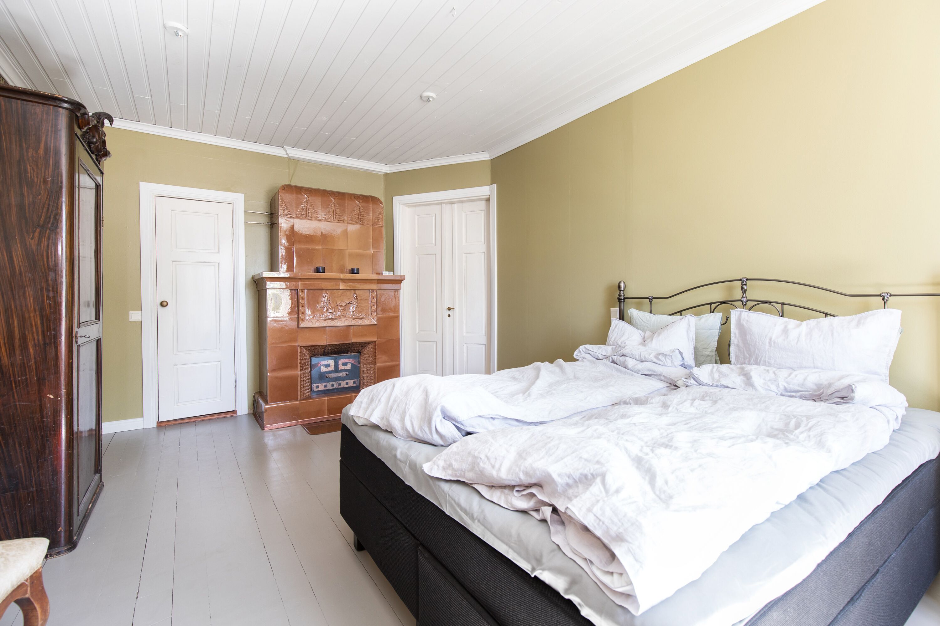 A bedroom with a bed, a wooden cabinet, and a fireplace.