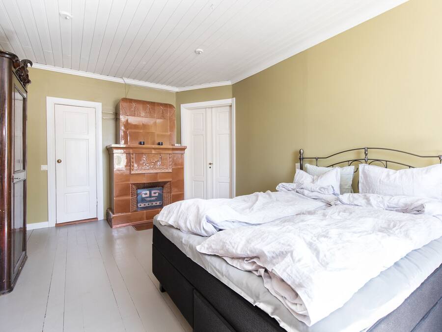 A bedroom with a bed, a wooden cabinet, and a fireplace.