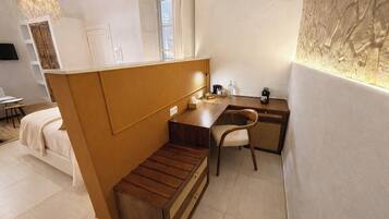 Une petite pièce comprenant un lit, un bureau en bois et une chaise.
