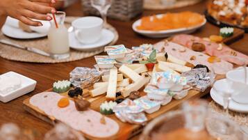 Una mesa de buffet con diversos quesos, embutidos y productos de pastelería.
