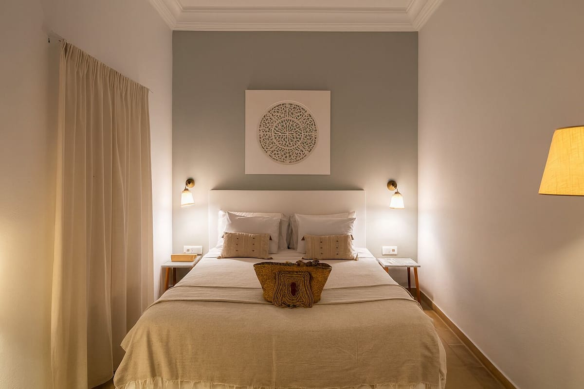 A neatly arranged bedroom with a large bed, two bedside tables, and a wall-mounted lamp.
