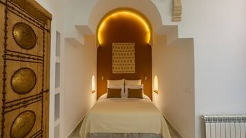 A bedroom with a bed centered under a large, illuminated archway.