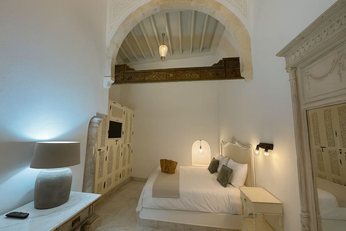 A bedroom with a bed, bedside tables, a lamp, and a wardrobe.