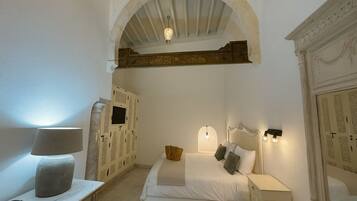 Un dormitorio con cama, mesitas de noche, lámpara y armario.
