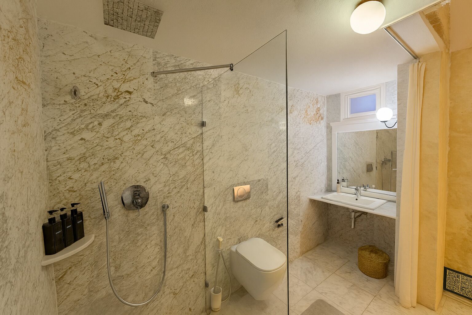 Un baño moderno con cabina de ducha de vidrio, inodoro y tocador con espejo.