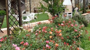 Un bâtiment en pierre avec un jardin à l’avant, des places assises à l’extérieur et un espace barbecue.