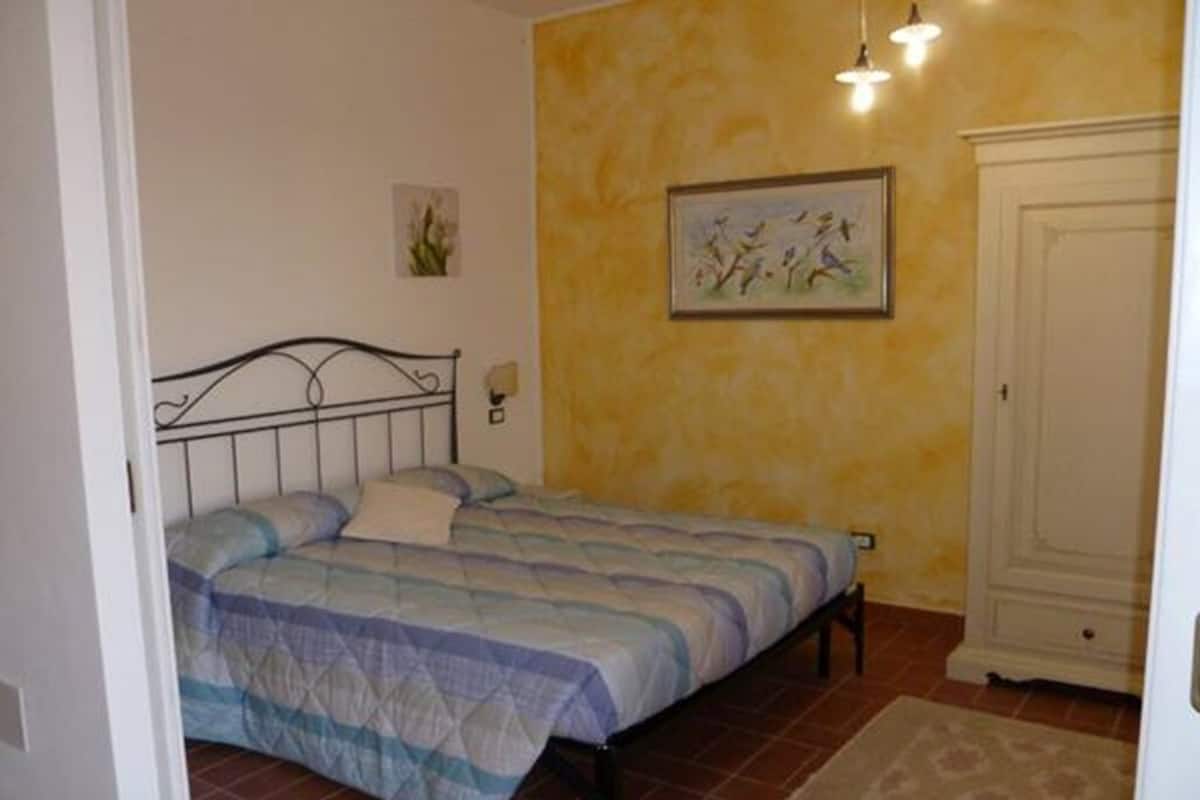 Une chambre à coucher avec un lit, une porte et un mur orné d’un tableau.