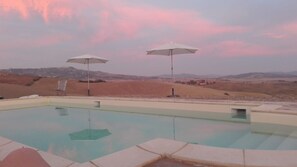 Una piscina al aire libre de temporada, sombrillas, tumbonas