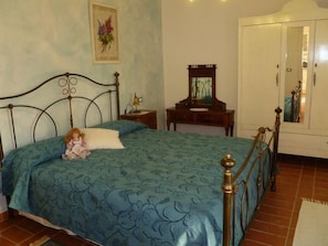 Une chambre à coucher avec un lit, une commode, un miroir et un tableau accroché au mur.