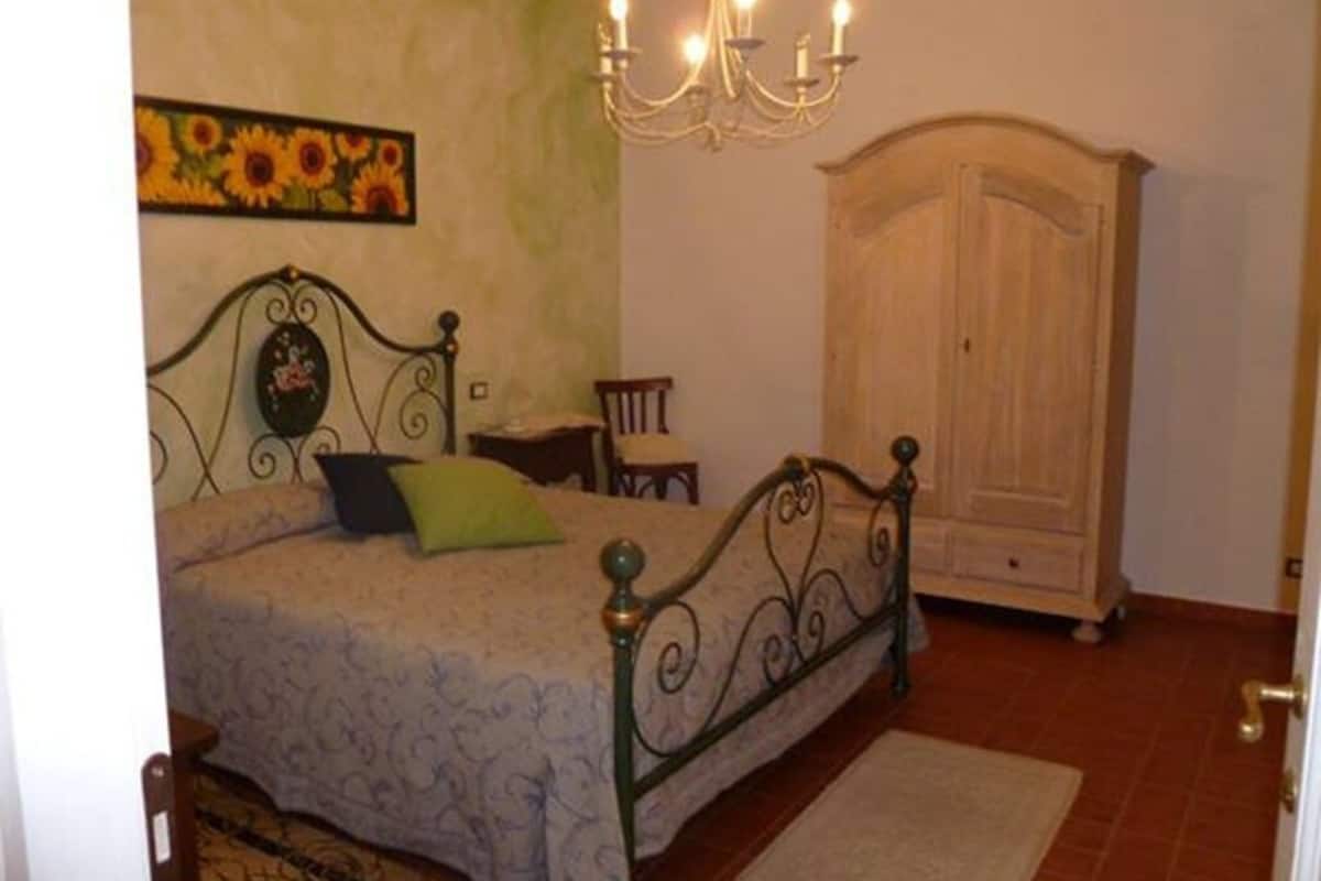 Une chambre à coucher avec un lit, un lustre, une armoire et un tableau au mur.