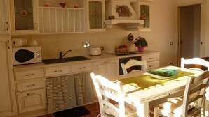 Une cuisine avec des meubles blancs, un four à micro-ondes, un évier et un coin repas comprenant une table et des chaises.