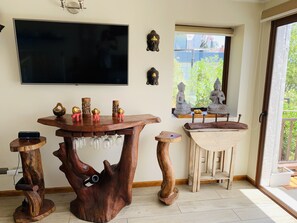 Une pièce avec une table basse en bois, un téléviseur et une fenêtre ornée de statues de Bouddha.