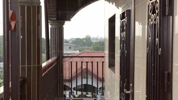 A corridor with a checkered floor leading to a balcony with a railing. - Residence MB Meublee (Douala)