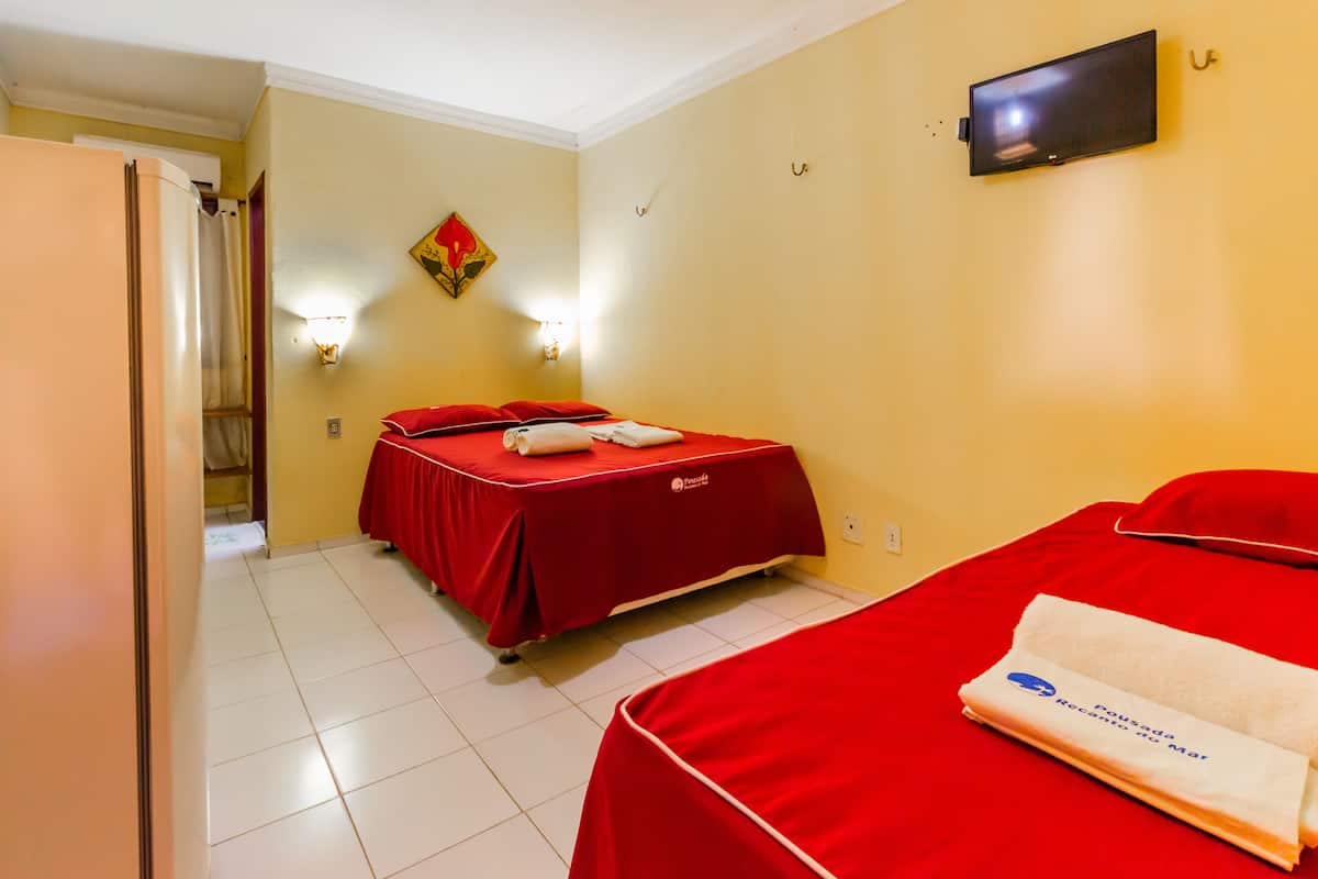 Habitación de hotel con dos camas, un televisor en la pared y zona de ducha.