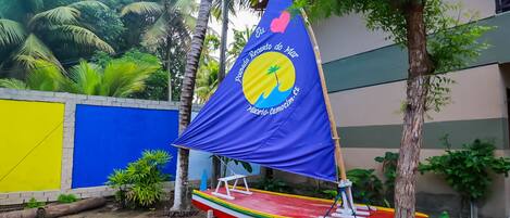 A colorful boat with a blue and yellow sail, docked near a building with a blue and yellow wall.