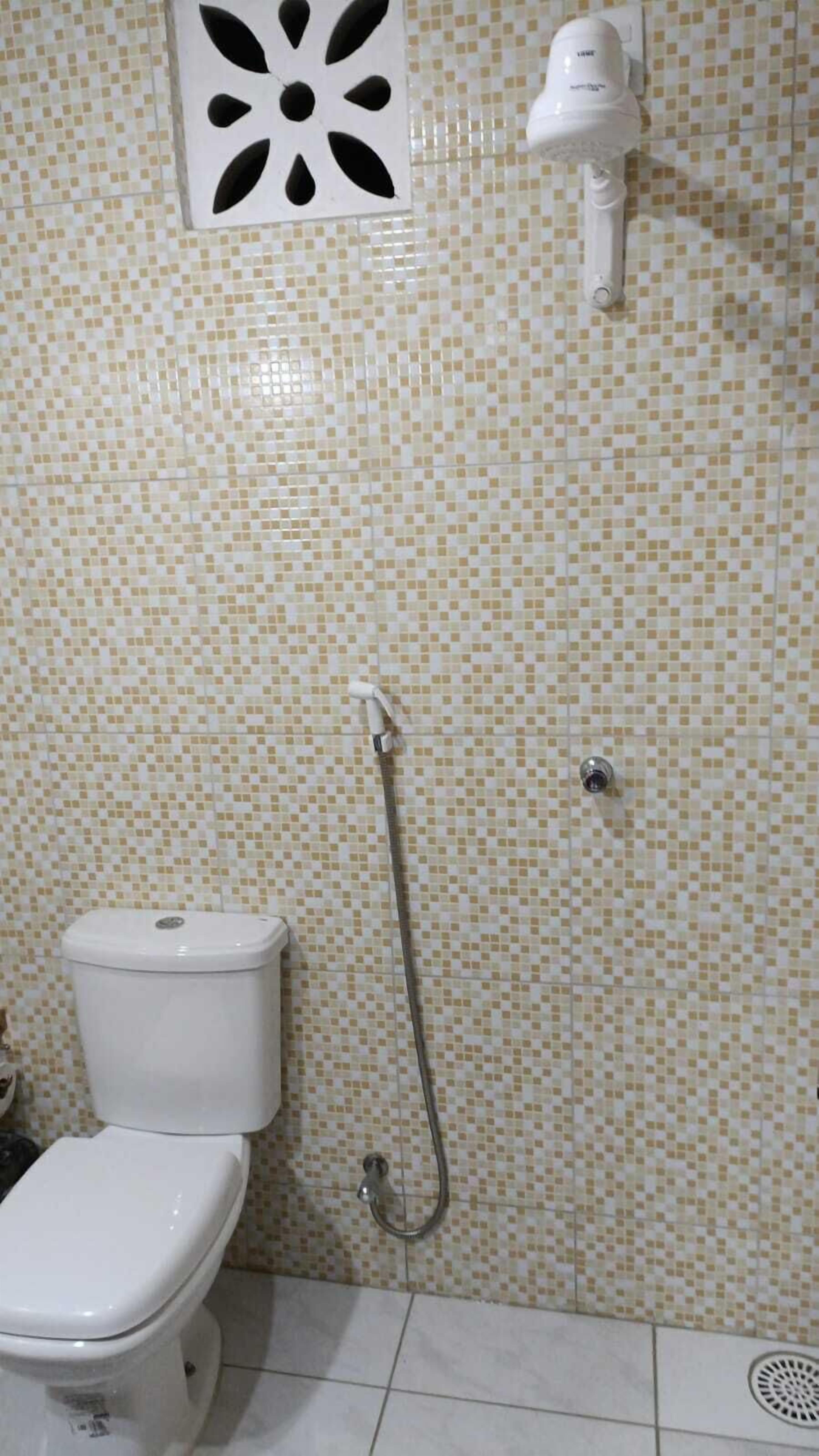 Un baño con inodoro, ducha y secador de pelo incorporado.
