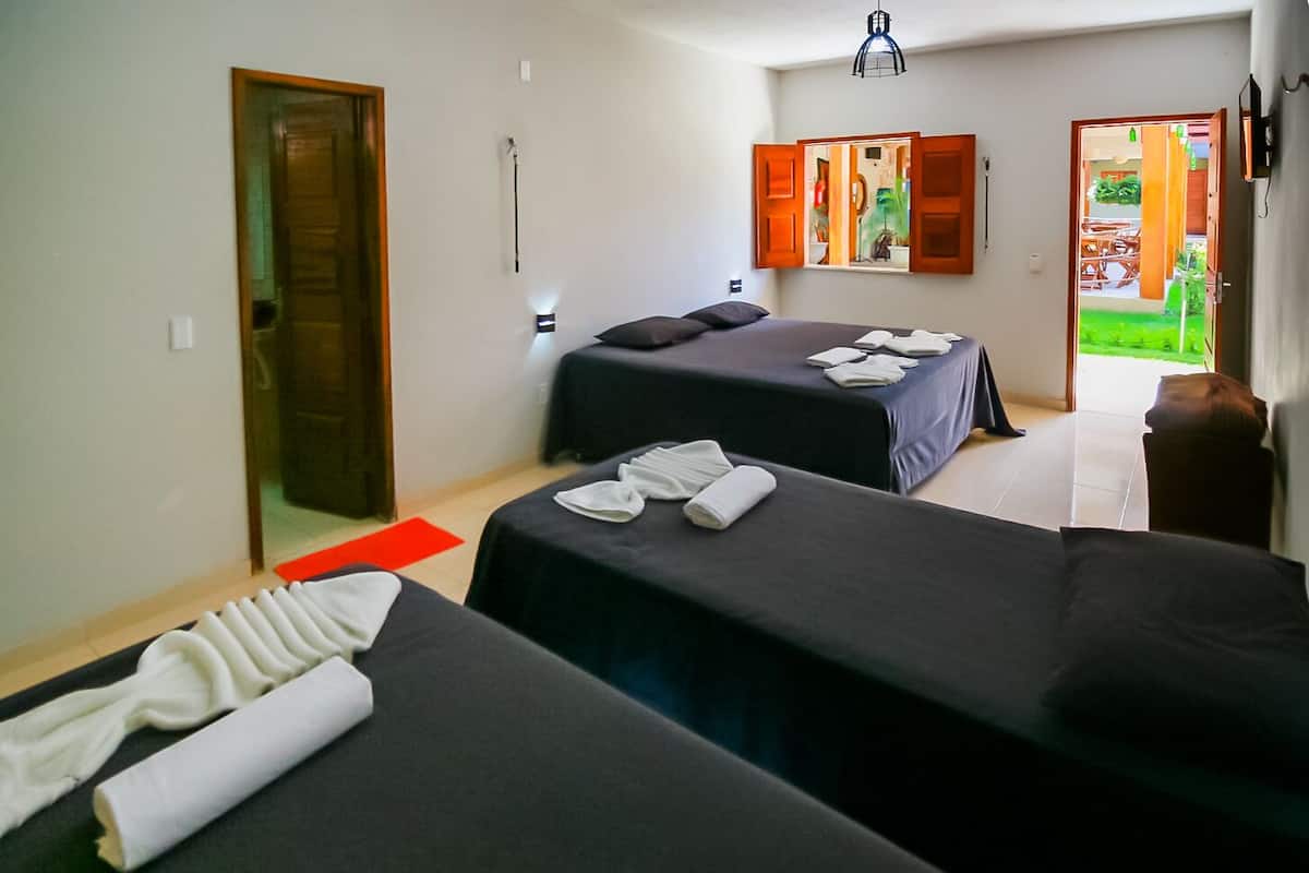 Habitación de hotel con dos camas, un tapete rojo, toallas, un espejo y vistas al jardín.