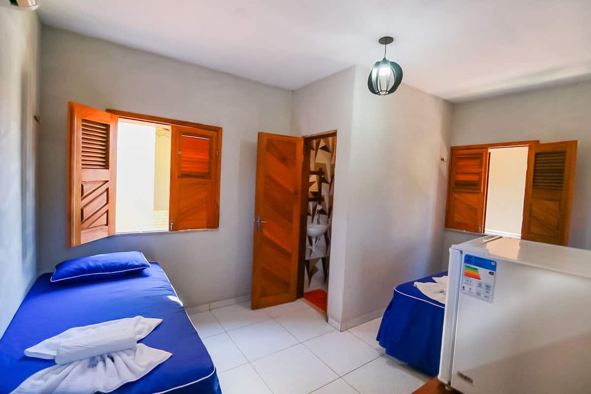 Habitación de hotel con dos camas, baño y refrigerador.