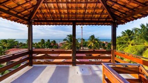 A covered outdoor area with a view of the ocean and palm trees. - Pousada Recanto do Mar (Camocim)