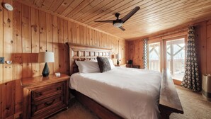 A wooden-paneled bedroom with a bed, nightstands, a desk, and a ceiling fan. - Luxe | Ski-In/Out | Hot Tub | Panoramic Views | EV (Beech Mountain)