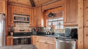 A kitchen with wooden cabinets, a microwave, a stove, and a sink. - Luxe | Ski-In/Out | Hot Tub | Panoramic Views | EV (Beech Mountain)
