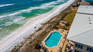 Vista aérea de una propiedad costera con piscina, acceso a la playa y vistas al océano.