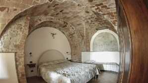 A room with a stone vaulted ceiling, a bed with a headboard, and a bedside table. - Agriturismo Alle Rose (Volterra)