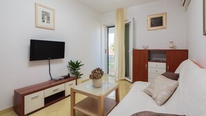 Uma sala de estar com televisão, sofá, mesa de centro e um armário de madeira.