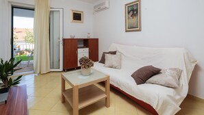 Um quarto com sofá, uma mesinha, um armário e um vaso de planta.