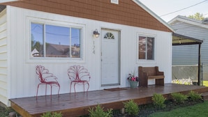 A small, single-story house with a front porch, two red metal chairs, a bench, and a potted plant. - Lake Erie House Near Cedar Point & The Beach (Huron)