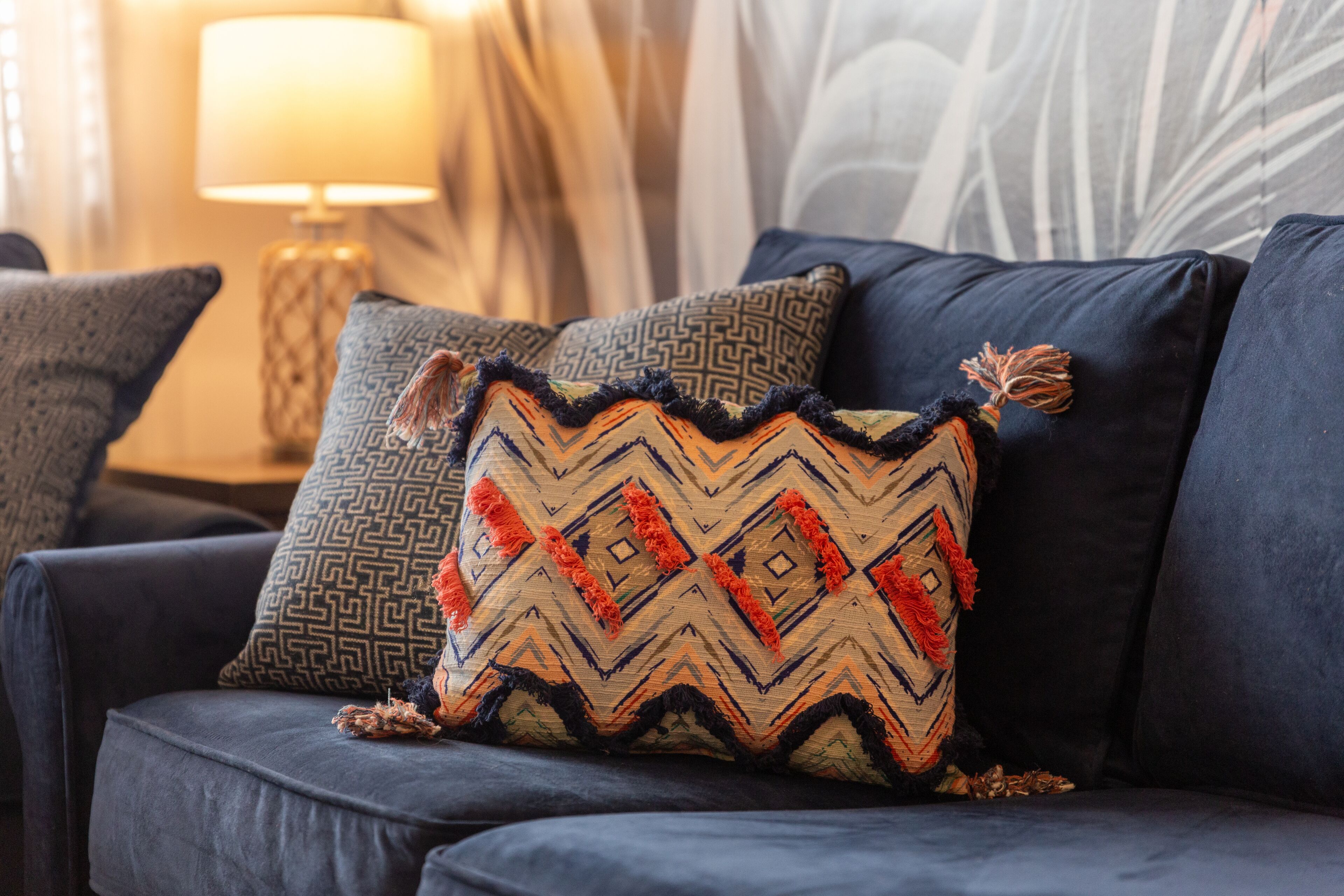 Un canapé bleu foncé agrémenté de coussins à motifs et d’un plaid décoratif.