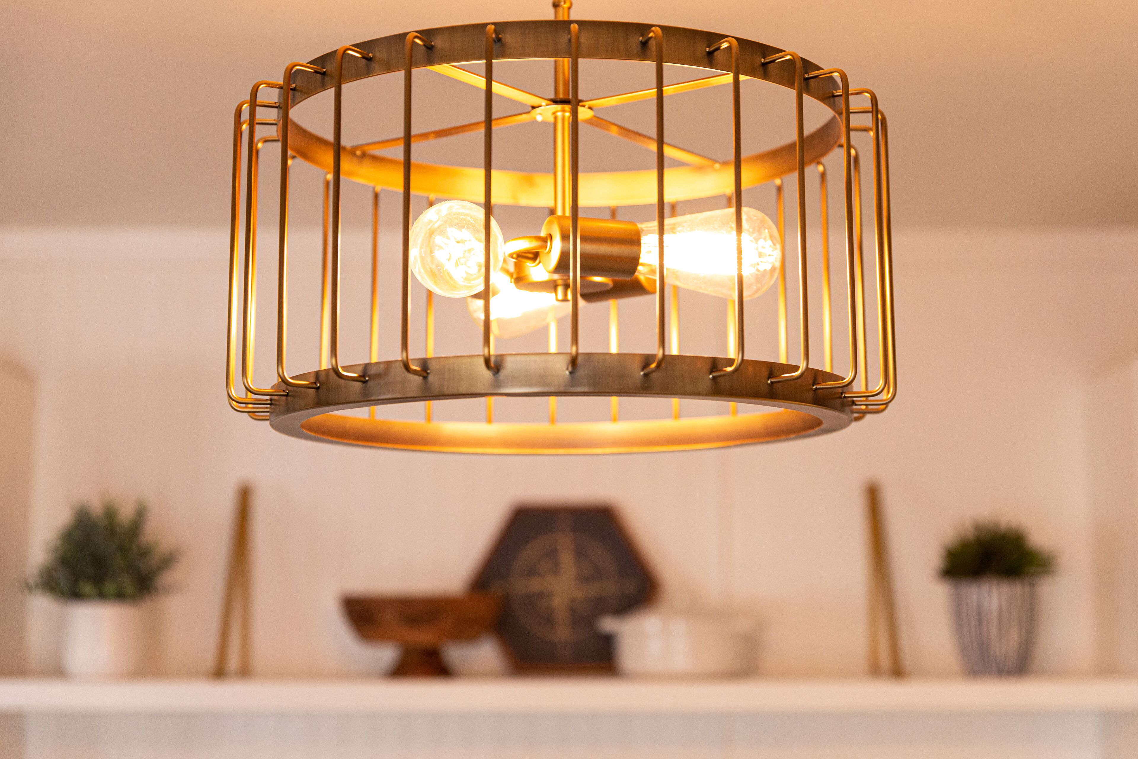 A modern chandelier with a cylindrical design and a metal cage structure.