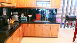 A modern kitchen with wooden cabinets, a black countertop, and various appliances. - T P Luxury House (Da Nang)