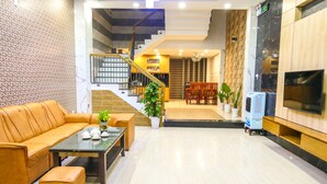 A modern living room with a sofa, coffee table, and a staircase leading to an upper floor. - T P Luxury House (Da Nang)